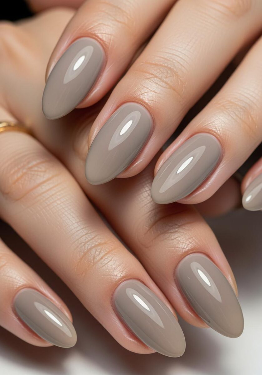 Close-up of two hands with glossy almond-shaped nails painted in a neutral taupe-gray polish