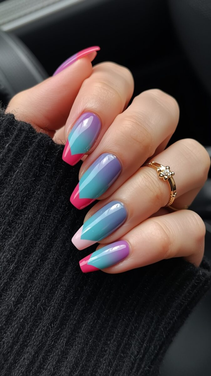 Hand with colorful geometric nail art featuring teal, purple, and hot pink chevron design on almond-shaped nails