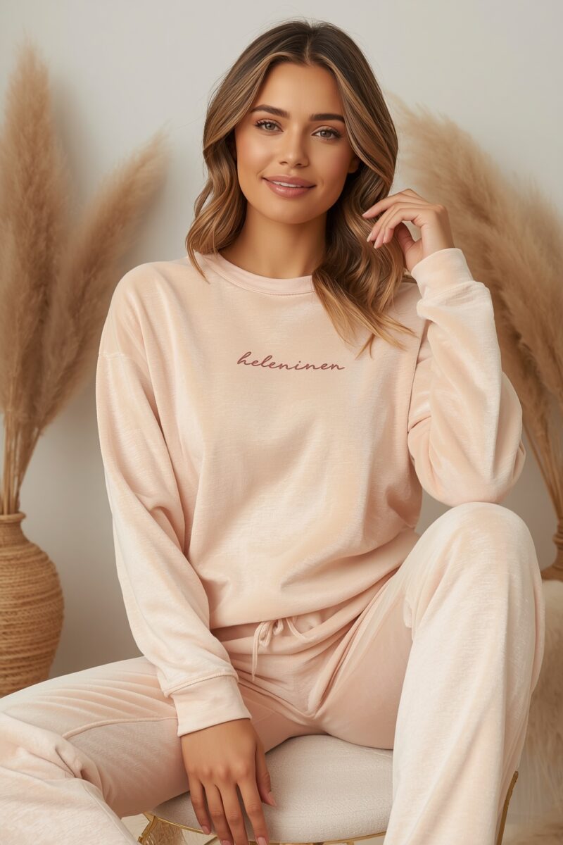 Woman wearing a blush pink Helen Inen branded sweatshirt and matching jogger pants, seated in a cozy styled setting