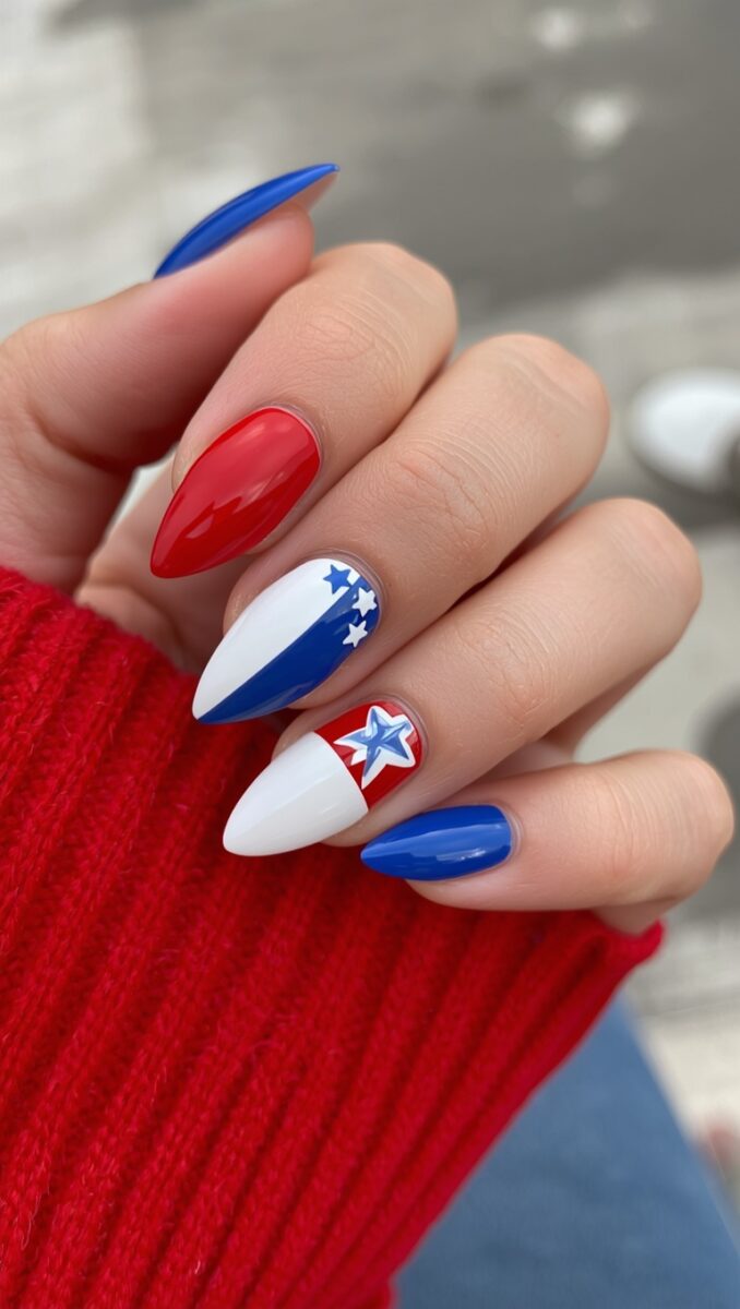 Hand with patriotic red, white, and blue almond-shaped nails featuring stars and flag-inspired nail art design