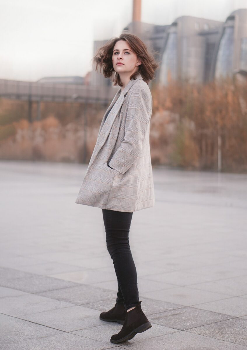 Woman in a long light check blazer, black skinny jeans and black suede Chelsea boots in autumn
