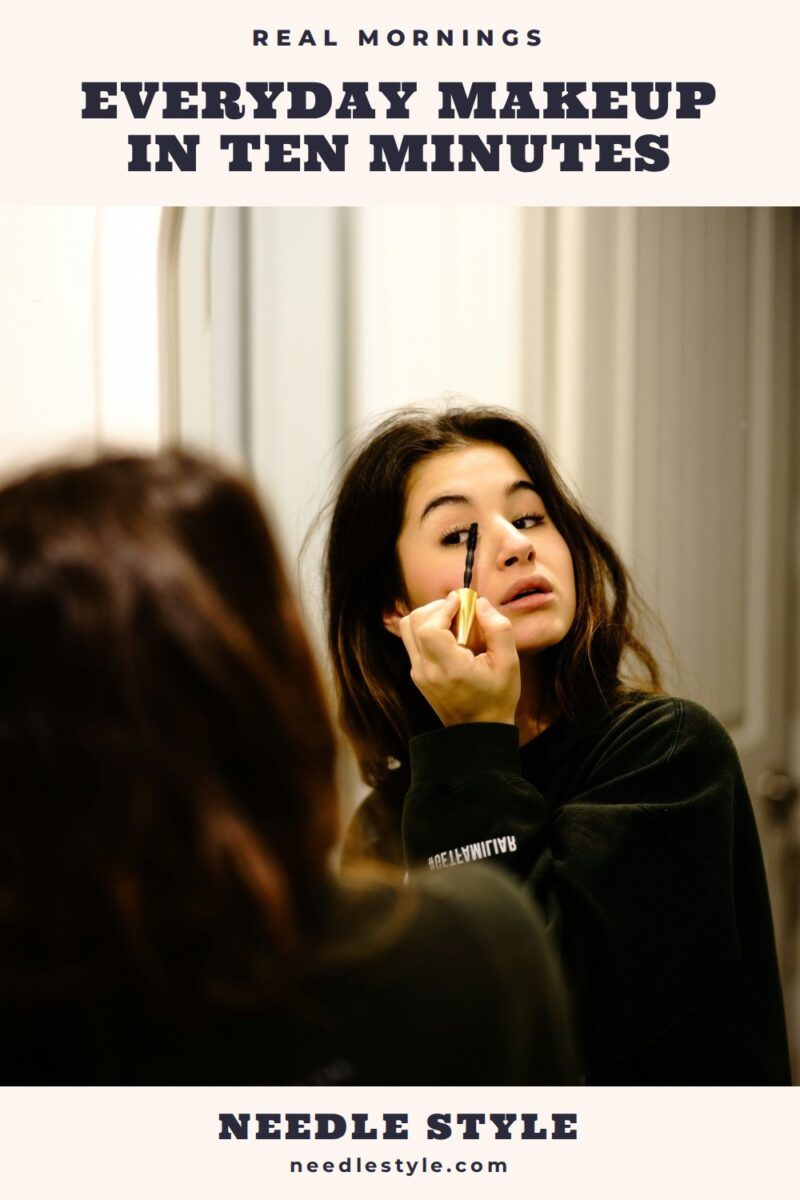 Everyday Makeup in Ten Minutes: A young woman in a black sweatshirt putting on mascara in a bathroom mirror