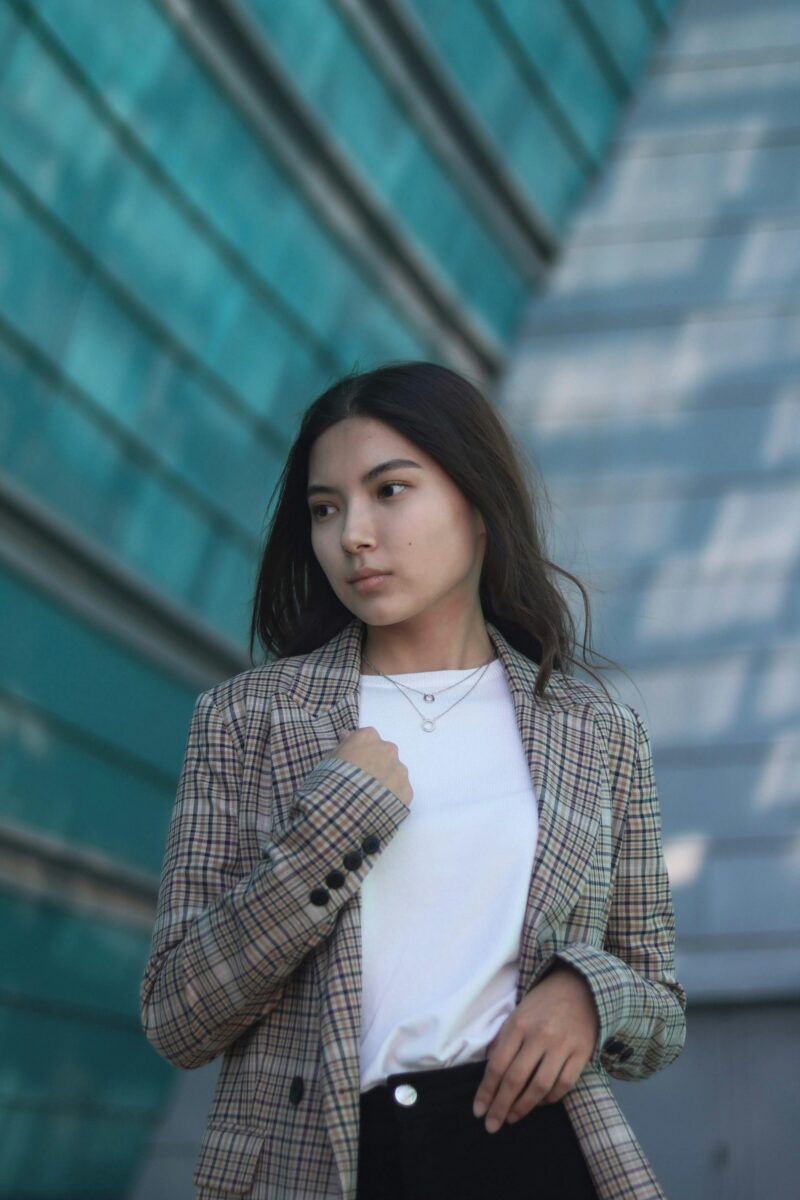 Woman in a brown check blazer worn open over a white crew-neck T-shirt and black jeans