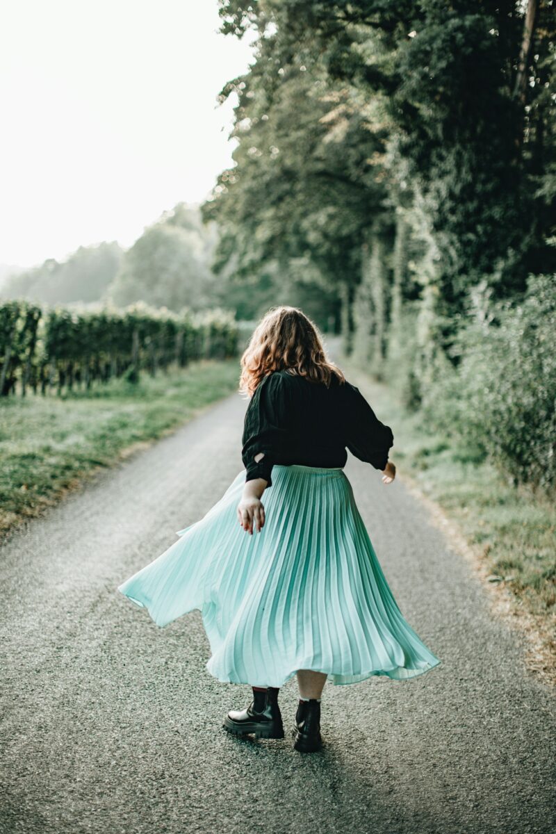 Midi skirt outfit for fall: a mint pleated midi skirt with a black sweater and chunky black ankle boots