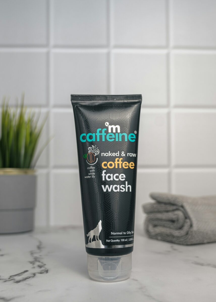 A tube of face wash and a folded gray hand towel on a marble bathroom counter against white tile