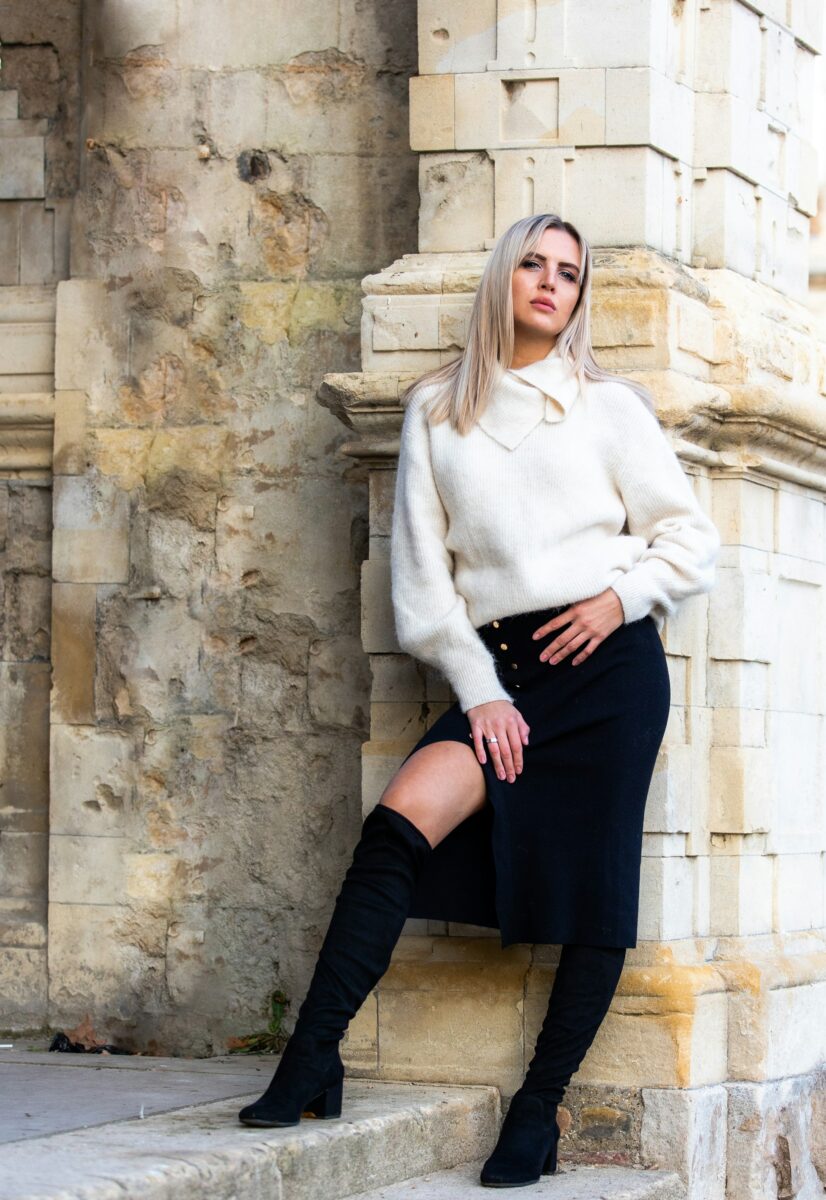 A black knit midi skirt with a side slit, a cream sweater and black suede over-the-knee boots that go up under the hem