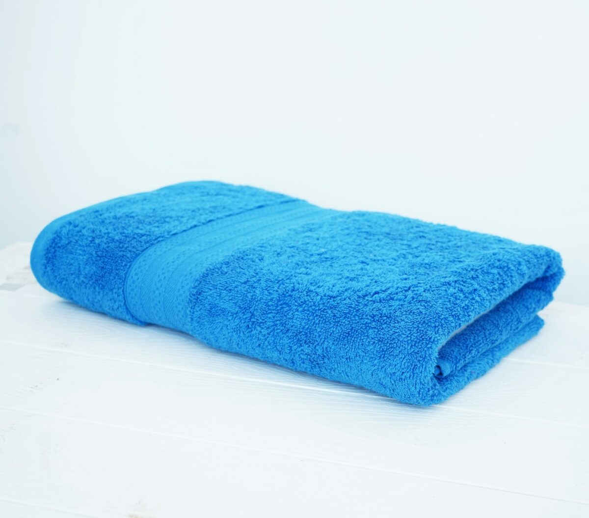 A folded blue cotton towel on a white table