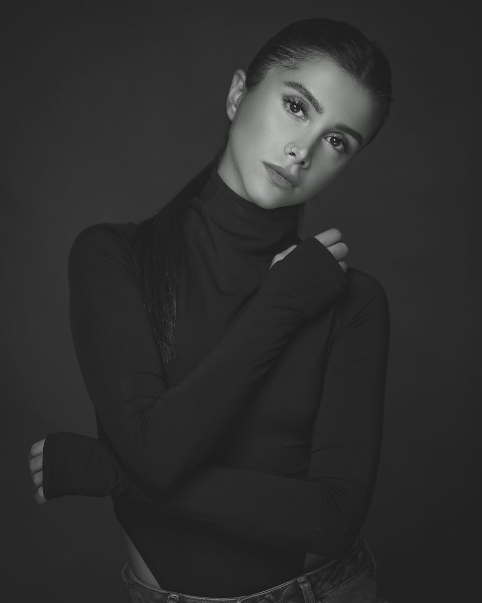 Black and white portrait of a woman in a fitted black turtleneck with long sleeves