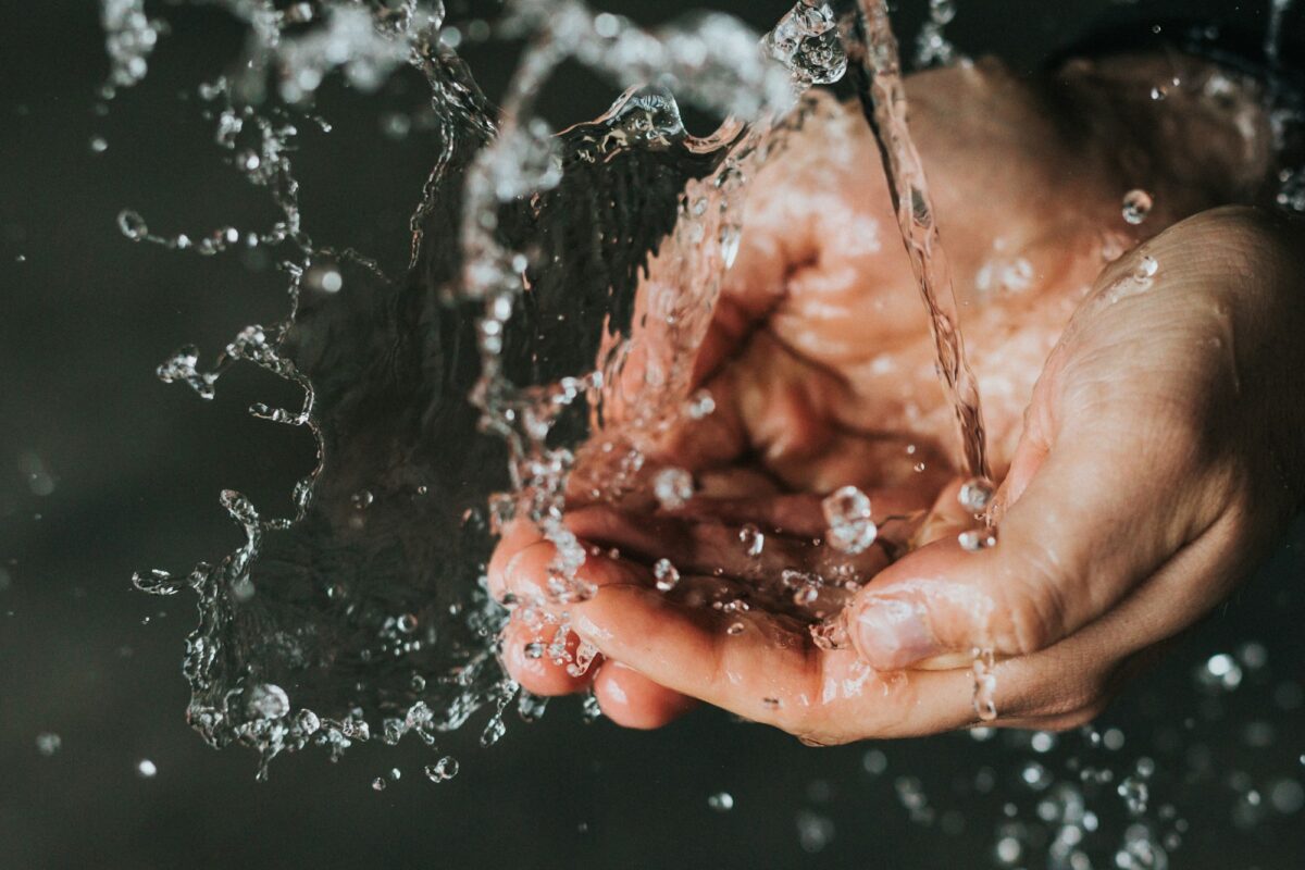 Cupped hands catching a stream of running water from a tap