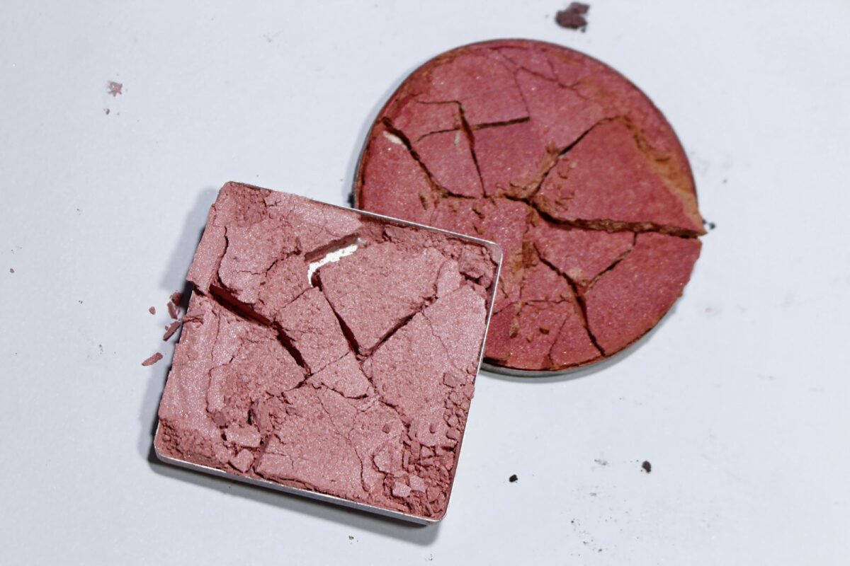 Two cracked pans of pink powder blush on a white surface