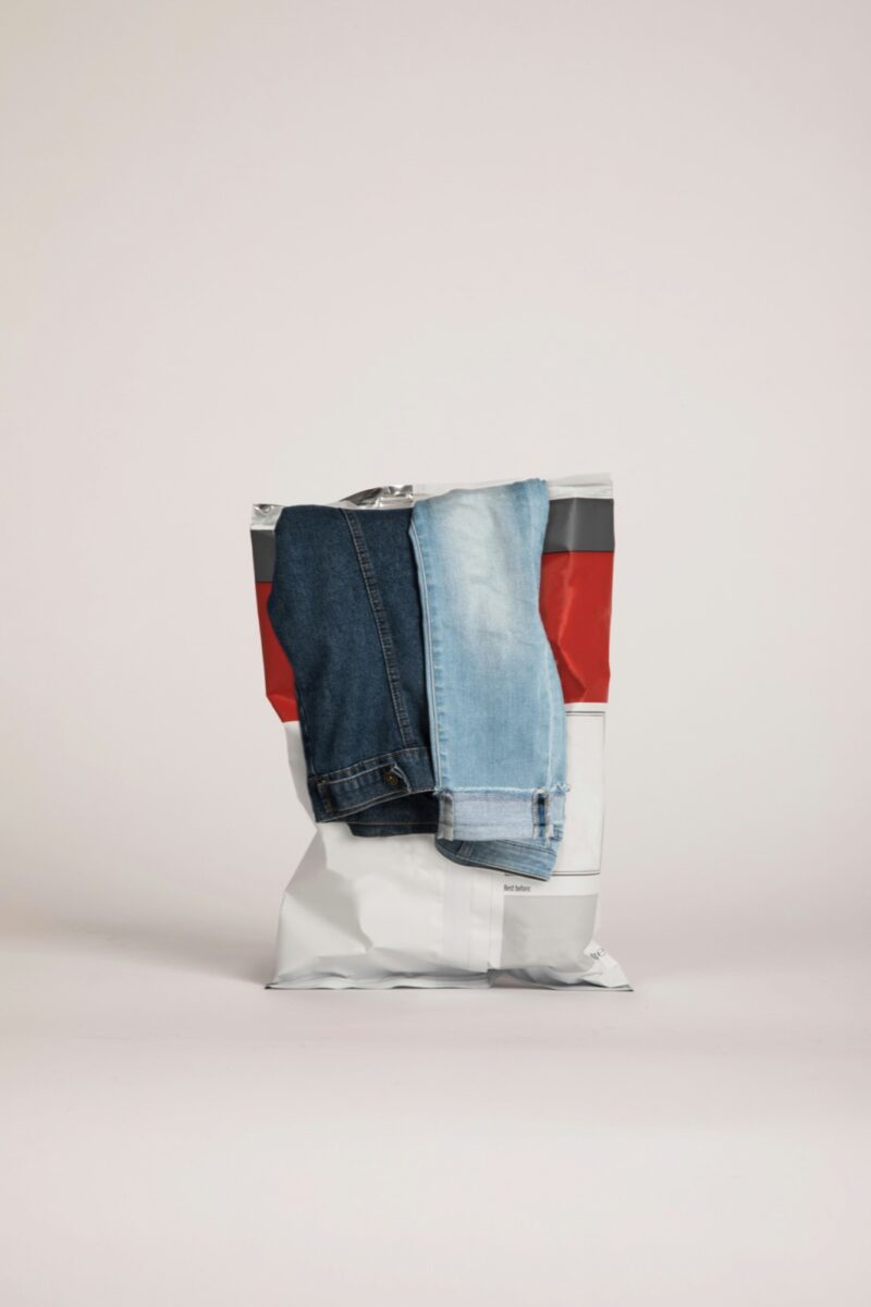 A dark pair and a light pair of jeans tucked into a white plastic mailer bag