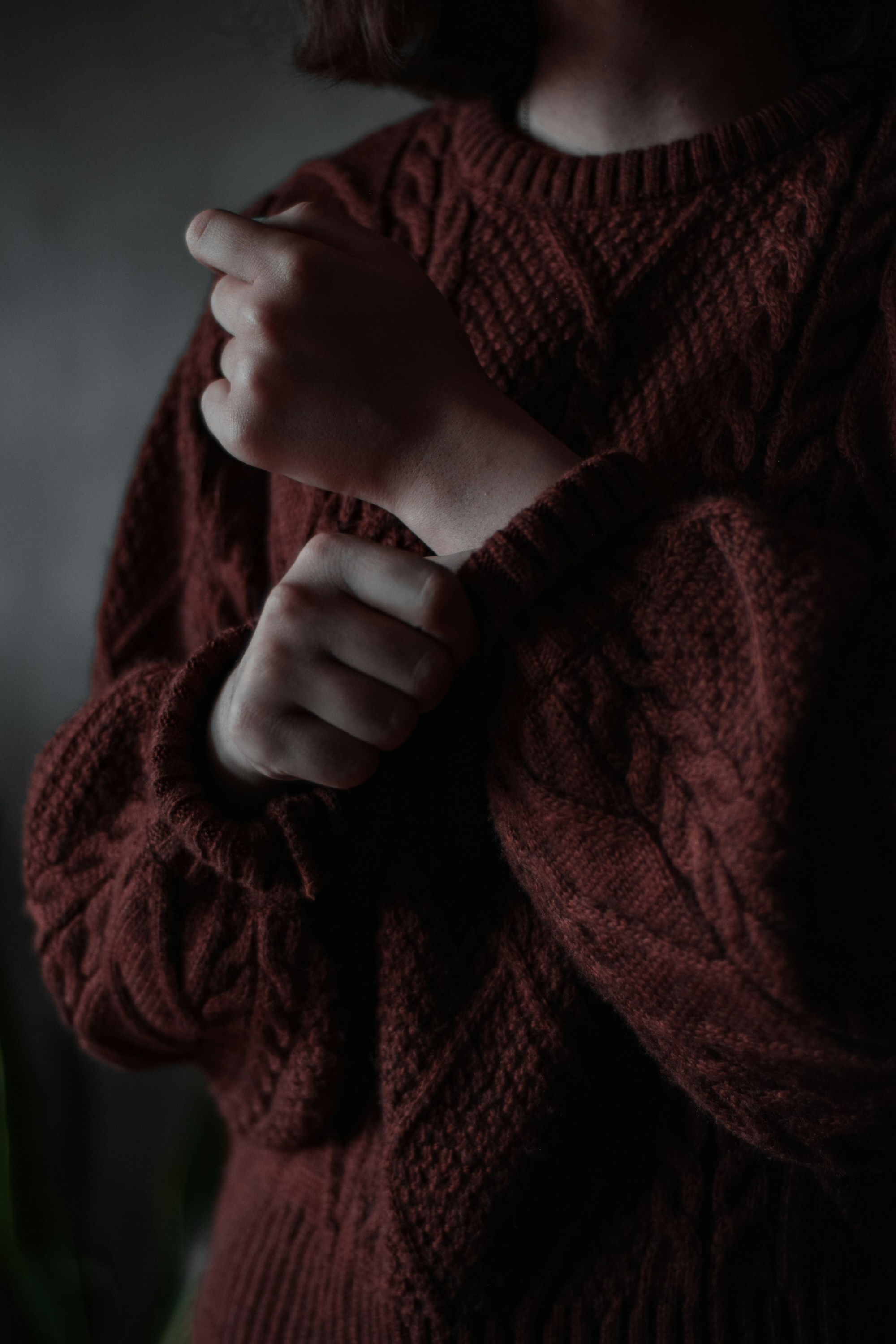 close-up of a rust cable knit sweater with diamond and moss stitch panels and a pulled-down sleeve