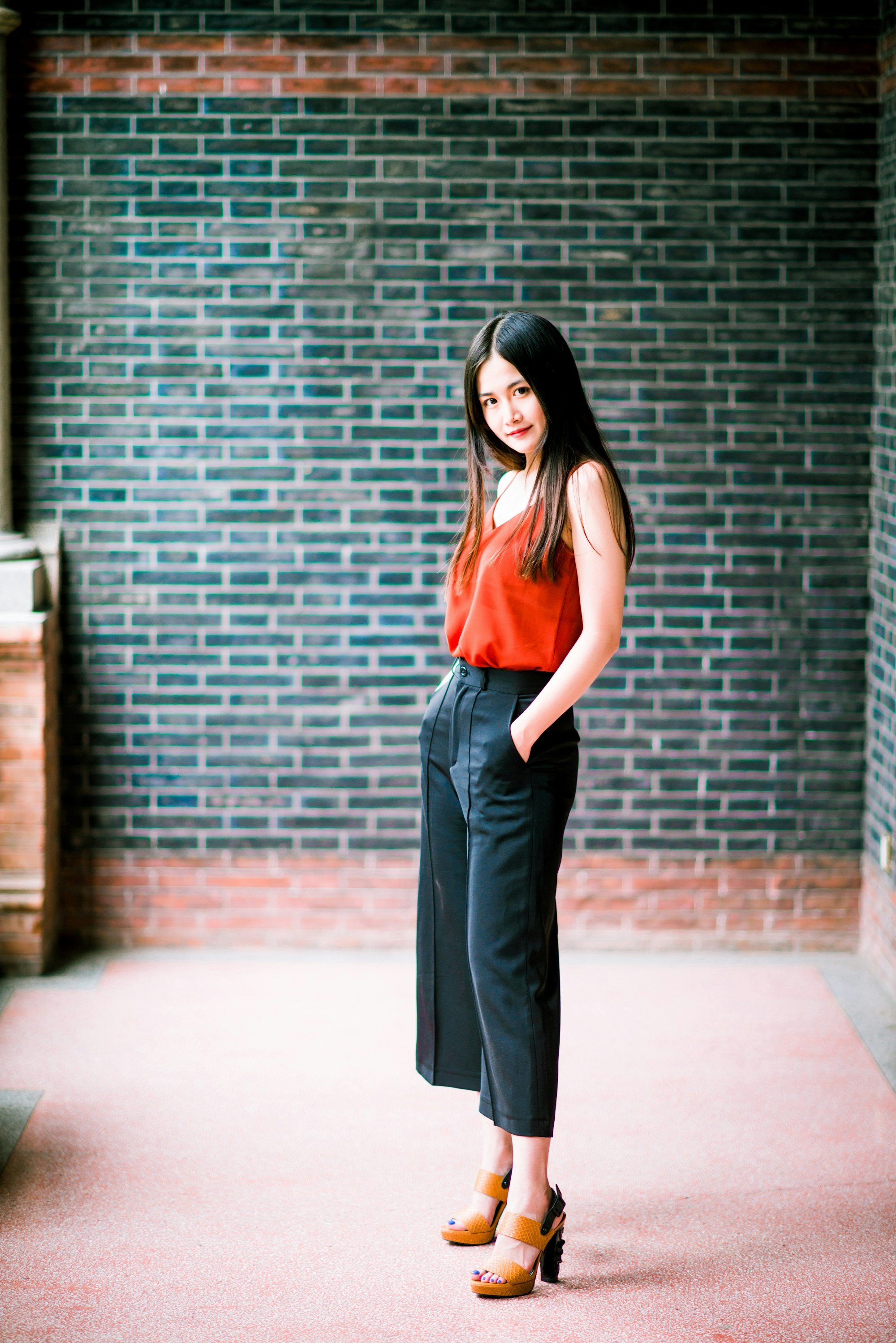 woman in a rust satin cami and black cropped wide-leg trousers with tan platform sandals