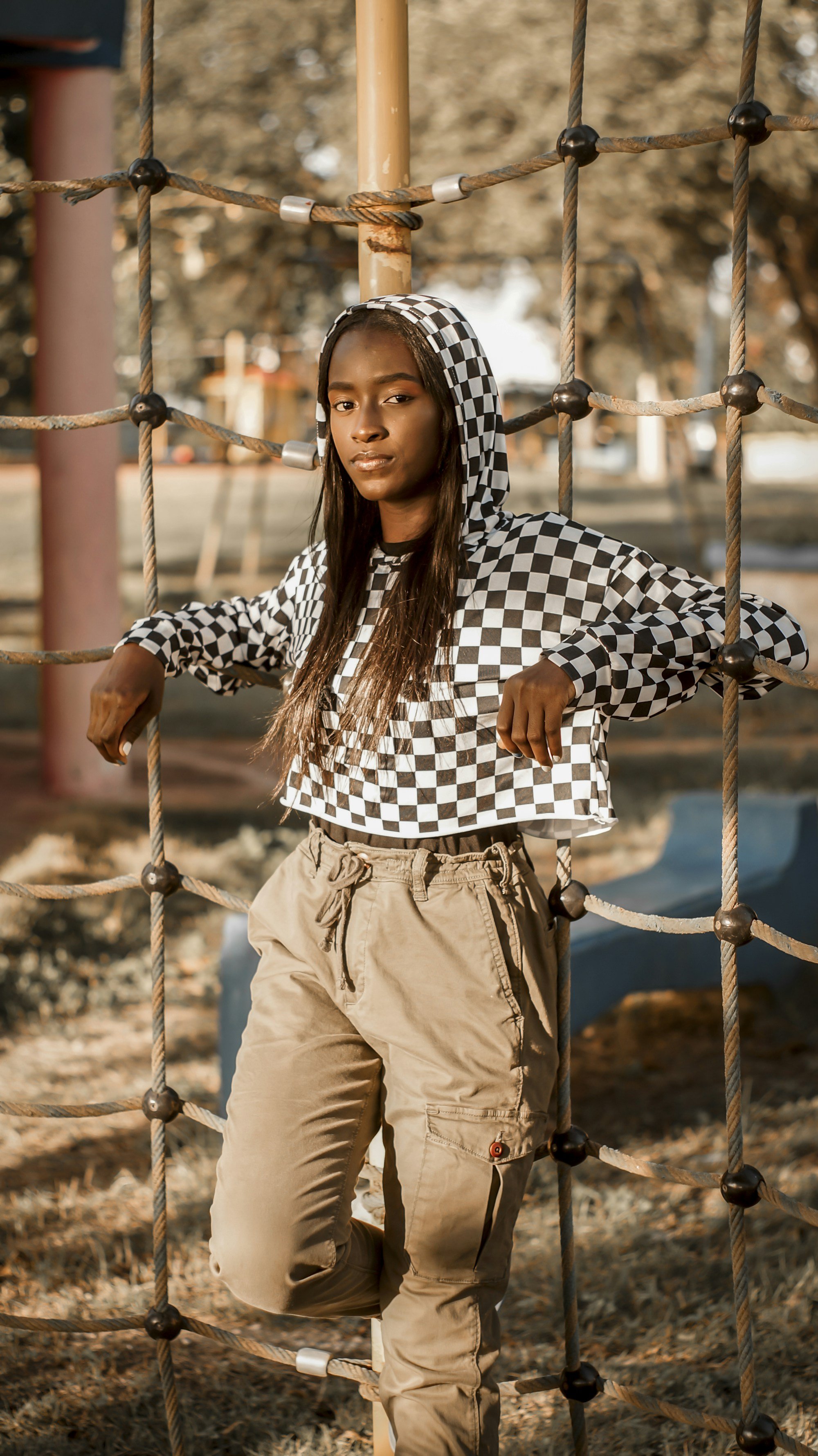 woman in a cropped black and white checkerboard hoodie and khaki cargo pants