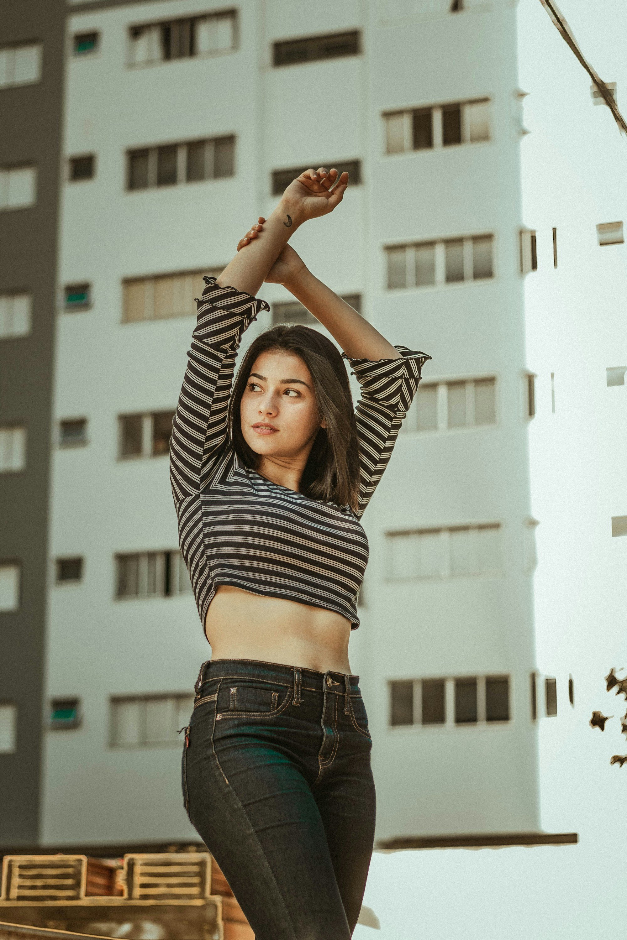 woman in a cropped black and cream striped long-sleeve top and dark high-waisted jeans