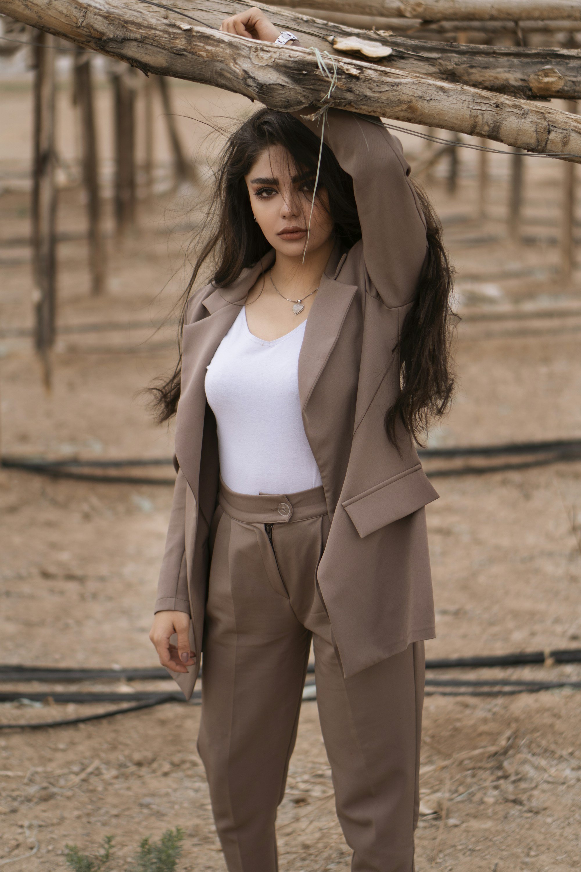 woman in a mocha suit with high-waisted creased trousers and a white scoop neck top