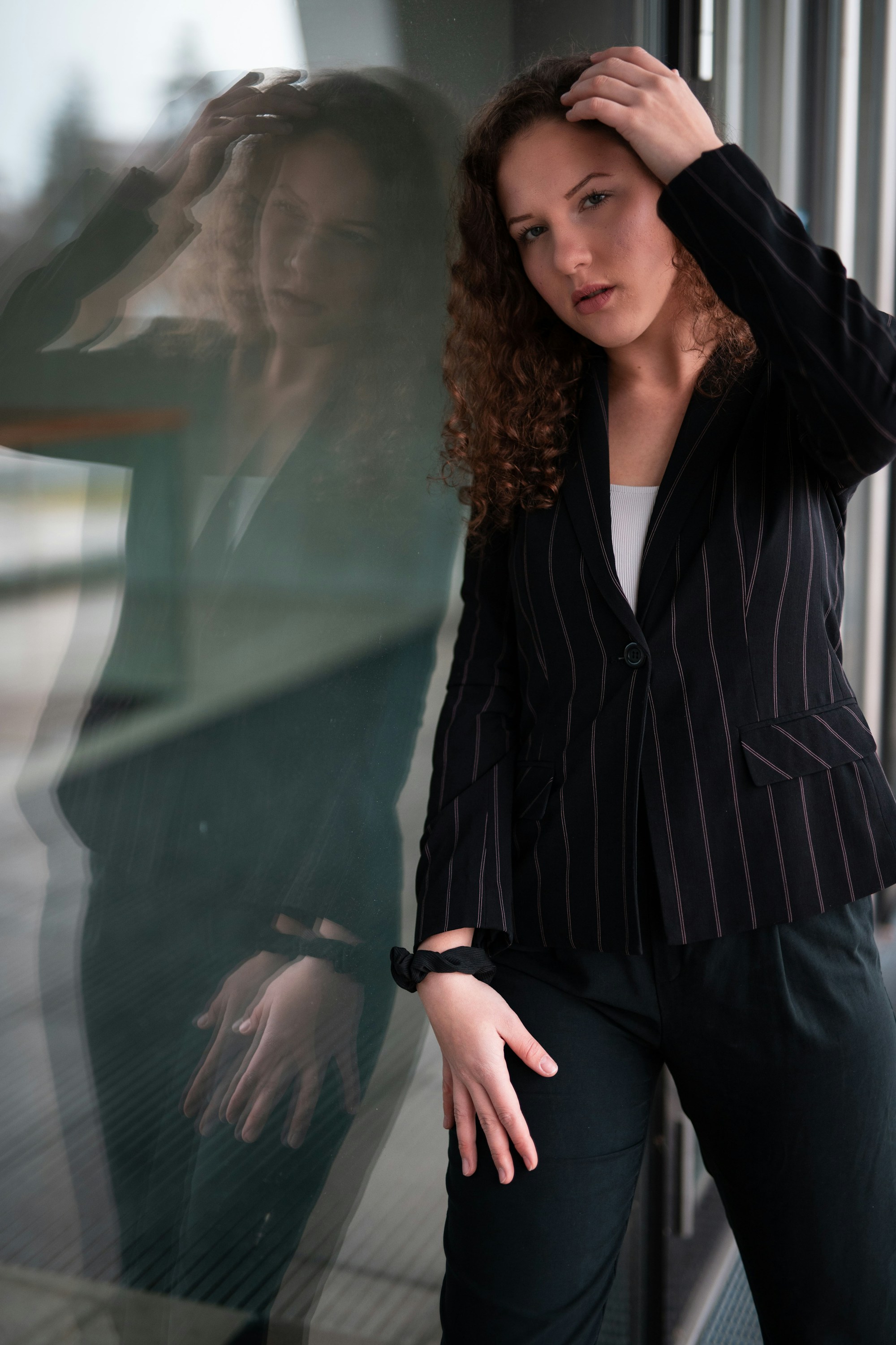 woman in a black pinstripe blazer over a white top with a black scrunchie on her wrist